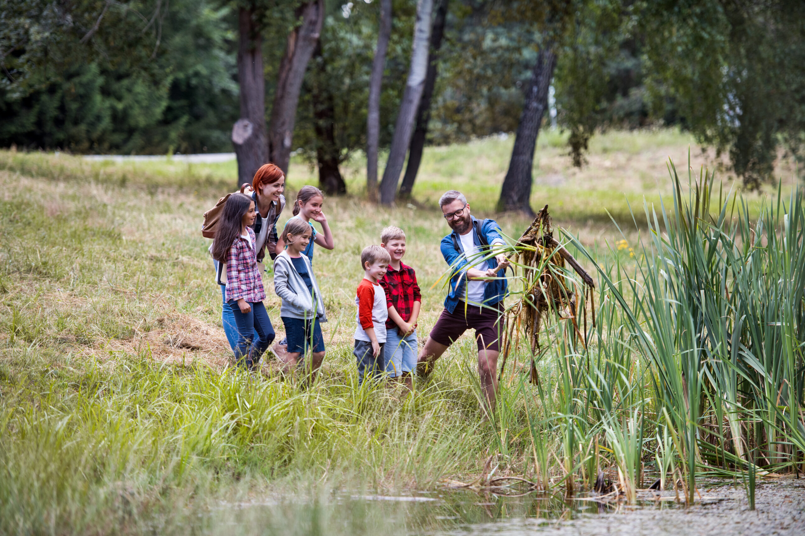 A group of small school children with teacher on field trip in nature.